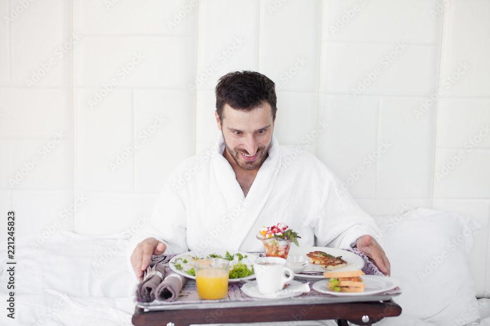 Happy single man eating breakfast in bed Happy single man eating breakfast in bed