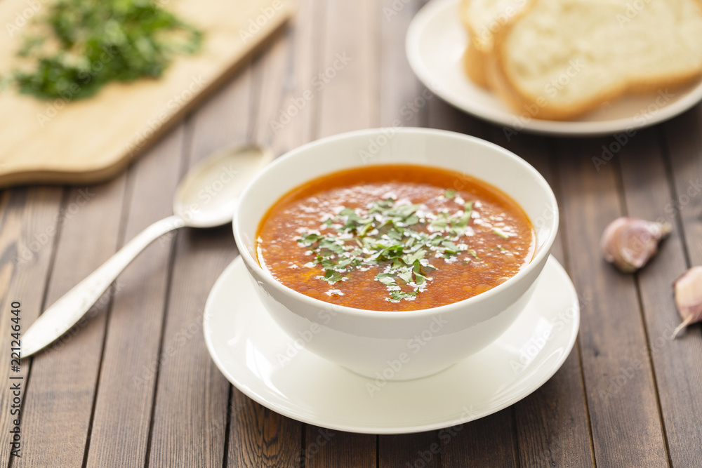 Chicken soup with vegetables and herbs in a white bowl on a wooden table Chicken soup with vegetables and herbs in a white bowl on a wooden table