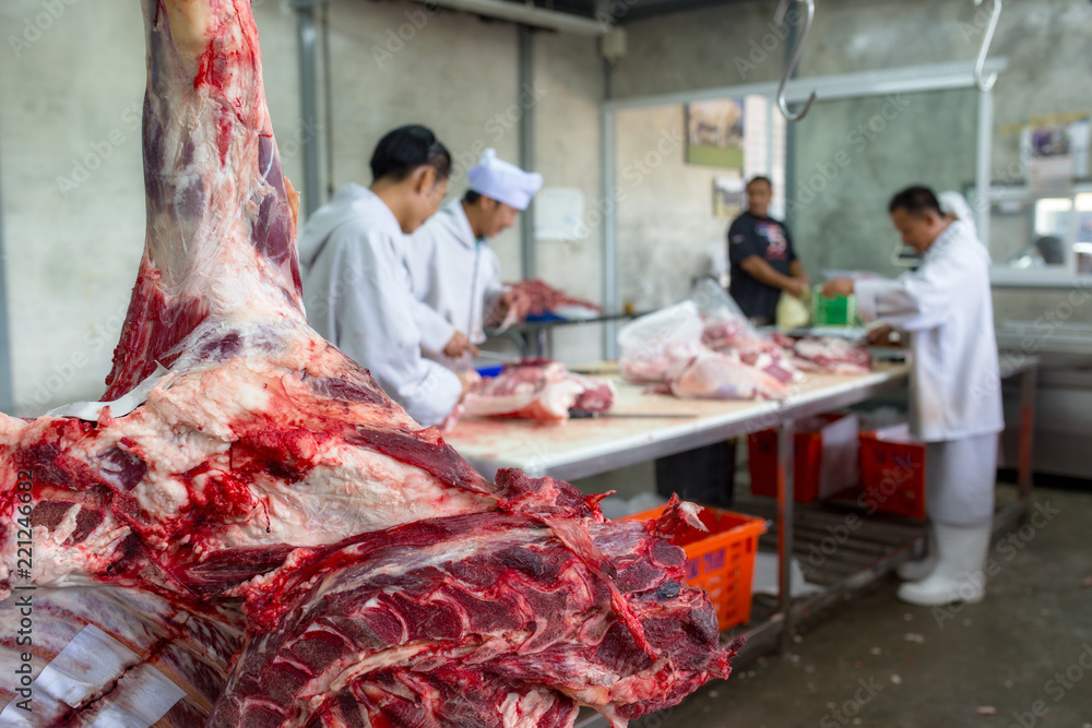 The butcher's closeup raw meat beef and blurred butcher working group The butcher's closeup raw meat beef and blurred butcher working group
