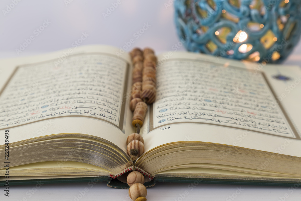 Fototapeta premium Quran and rosary on the white background with blue candle for Islamic concept. Holy book Koran for Muslims holiday, Ramadan,blessed Friday message and three months