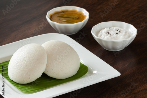 Indian idly with chutney and sambar - Fresh steamed Indian Idly (Idli / rice cake) arranged on banana leaf lined plate. Served with coconut chutney and sambar. Natural light used.