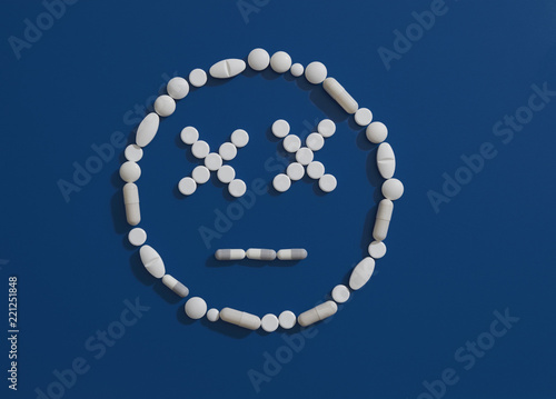 Pills forming dizzy face on blue background