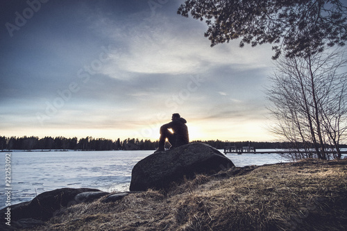 Man sitting on rock overlooking Lake Nydala, Umea, Sweden photo