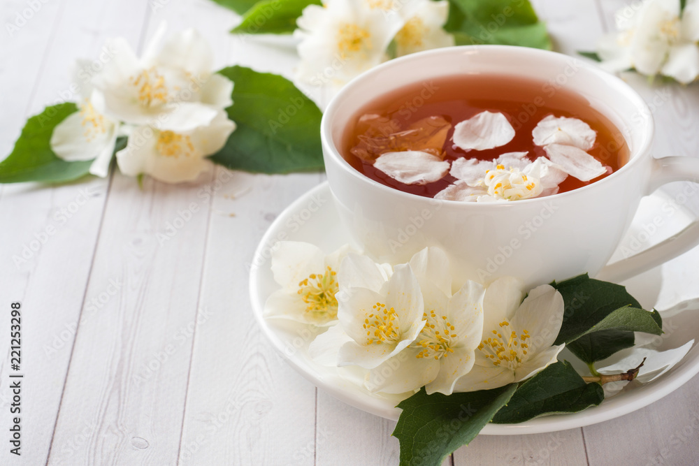Mug of herbal tea with petals of Jasmine flowers on a light background. Mug of herbal tea with petals of Jasmine flowers on a light background.