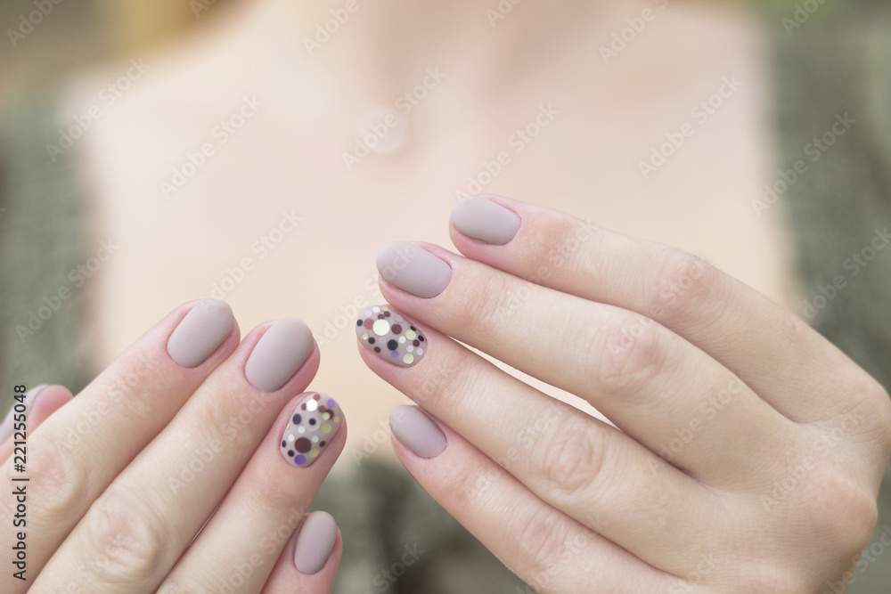 manicure, nails, nail art design gel nail polish on two hands gray neutral  light color with dots of sequins on the ring finger of black, silver, brown  and purple Stock Photo |