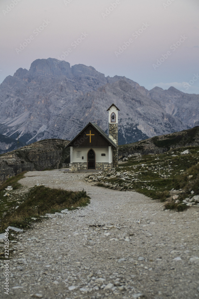 Breathtaking summer scenic landscape view of iconic Cappella degli Alpini chapel while sunrise in famous Tre Cime di Lavaredo mountains in the Dolomites mountain range, South Tirol Alps, Italy, Europe