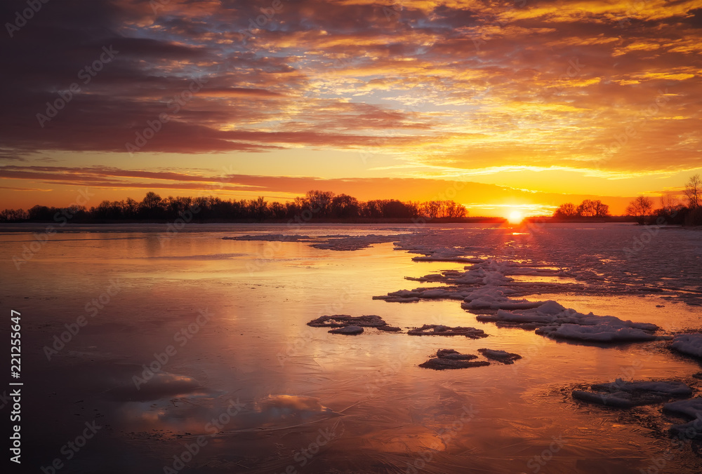 Beautiful colorful winter landscape with frozen lake and sunset sky. Unusual weather phenomenon