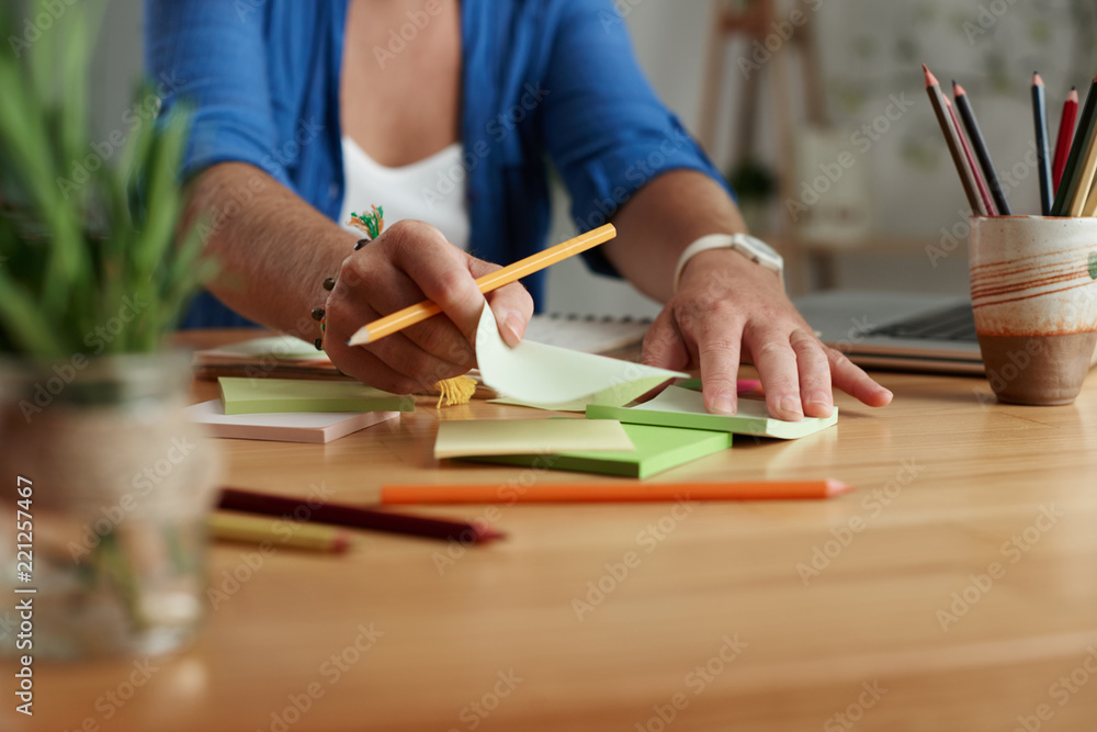 Woman using sticky notes when working on some project at her table Woman using sticky notes when working on some project at her table
