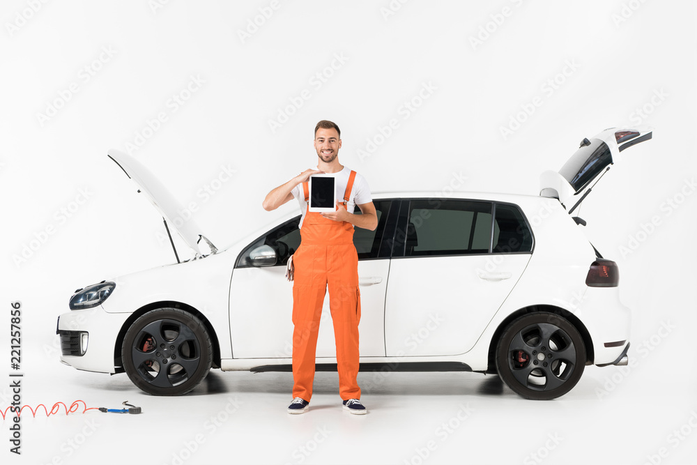 handsome auto mechanic showing tablet with blank screen near broken car on white handsome auto mechanic showing tablet with blank screen near broken car on white