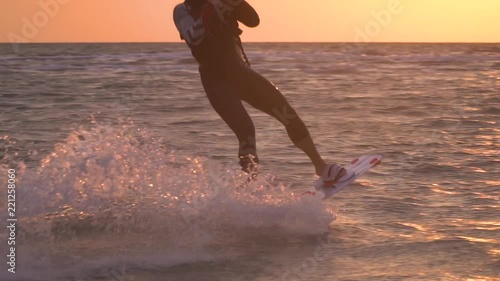 A man clings to the trapezoid of a training kite, a red wakeboar. Slow motion photo