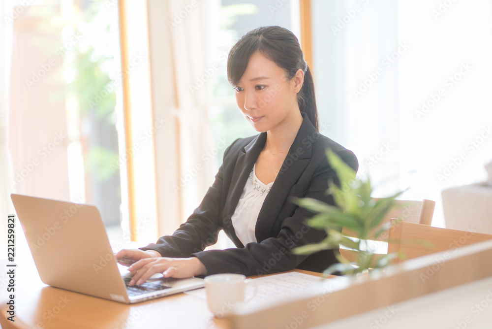 ノートパソコンで仕事をするスーツ姿の女性