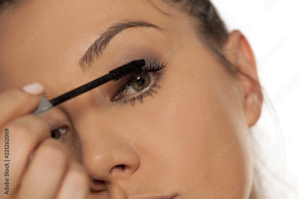 Closeup of young woman applying mascara