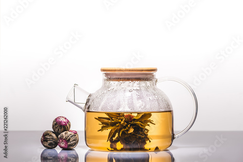 glass teapot of chinese flowering tea with tea balls on table photo