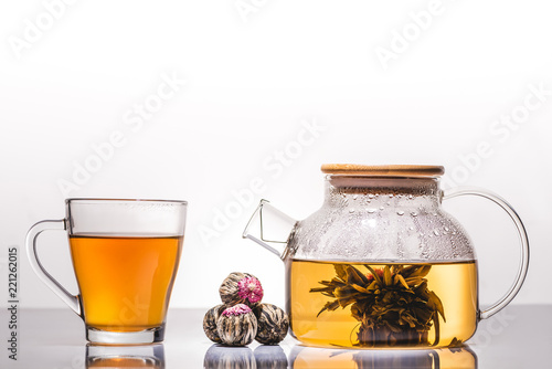 cup and teapot of chinese flowering tea with tea balls on table