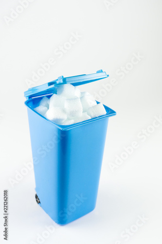Blue trash can full of sugar cubes, white background