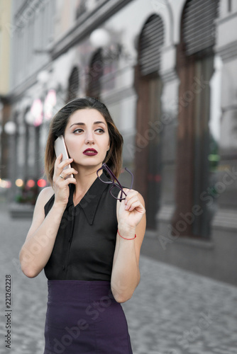 Beauty business lady with a mobile phone in the street with office buildings in the background