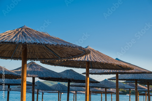 Straw covered umbrella on the beach with turquoise water in the background