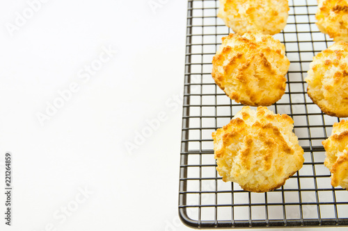 Homemade Delicious Coconut Macaroons Cookies with Golden Crust on Black Metal Cooling Rack White Kitchen Table. Christmas Pastry Baking Desserts. Recipe Template with Copy Space