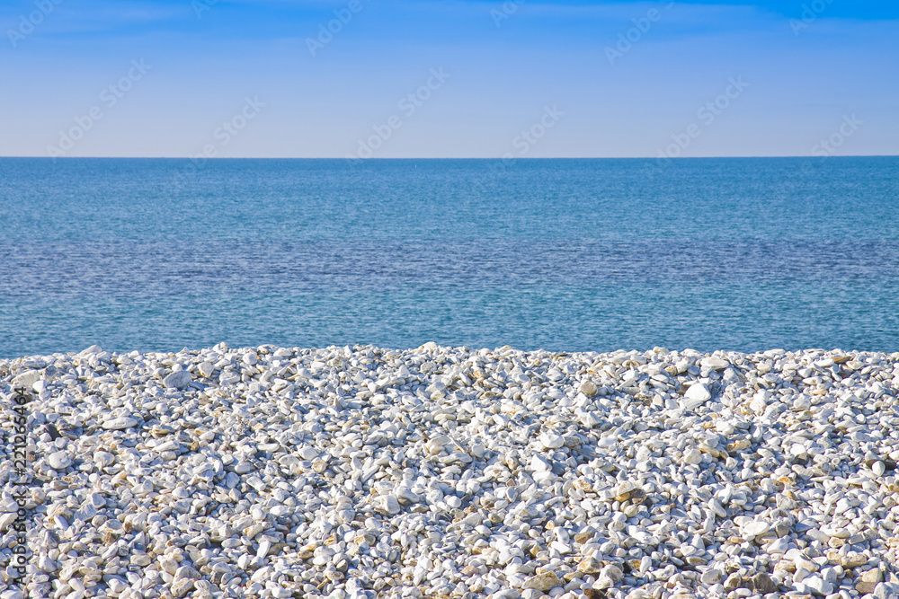 Expanse of white gravel on the sea coast with calm sea on background Expanse of white gravel on the sea coast with calm sea on background