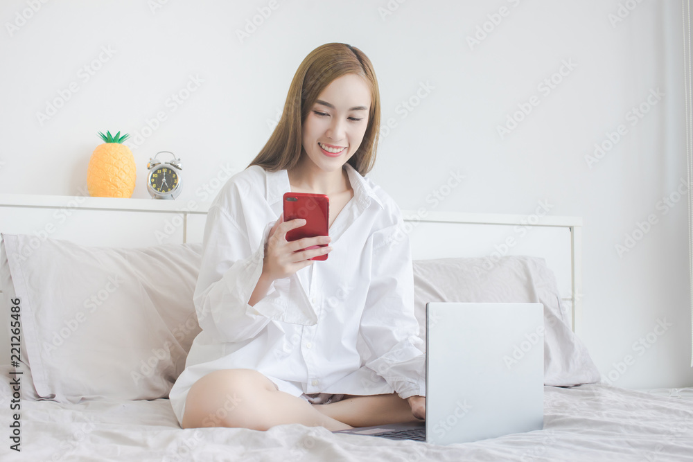 Beautiful Woman use of cellphone and laptop computer on bed Beautiful Woman use of cellphone and laptop computer on bed