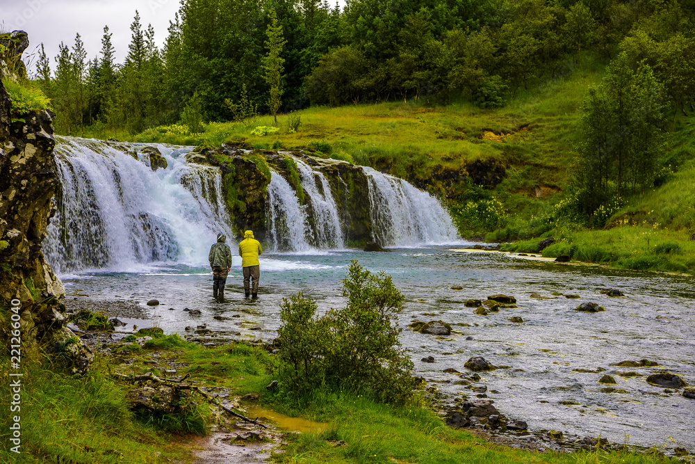 Fishermen fly fishing at fast flowing waterfall