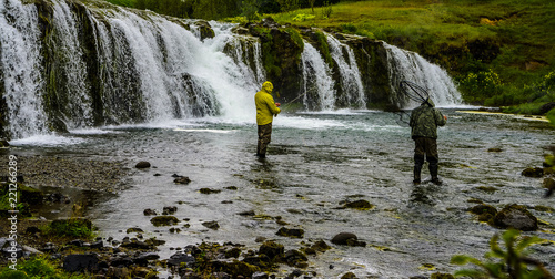 Fishermen fly fishing at fast flowing waterfall