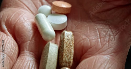 Senior Woman open her palm and we see set of tablets. Many pills on old woman palm. Macro shot.