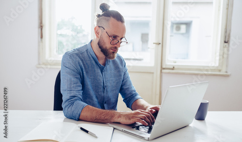 Young businessman working on laptop / Young man working on his desk.