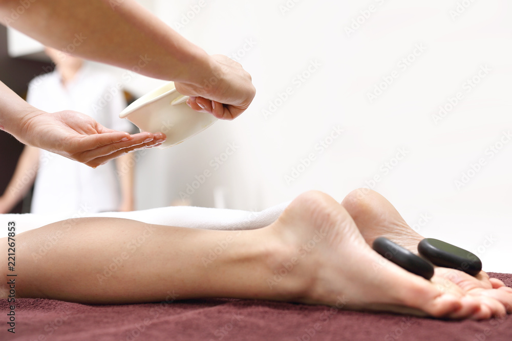Masaż kamieniami. Kobiece stopy z kamieniami bazaltowymi, relaks w salonie  spa. Stock Photo | Adobe Stock
