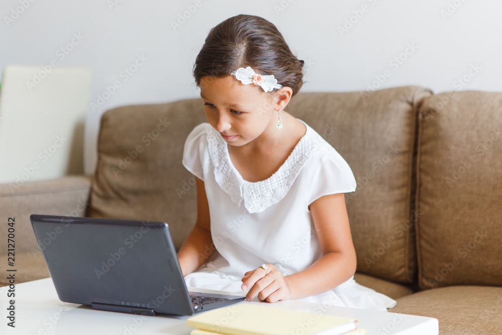 Beautiful, elegant girl 8 years old is engaged in home in an online school.

