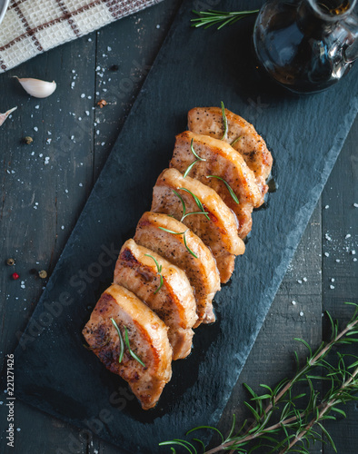 Roasted pork chops with fresh rosemary on dark background, top view