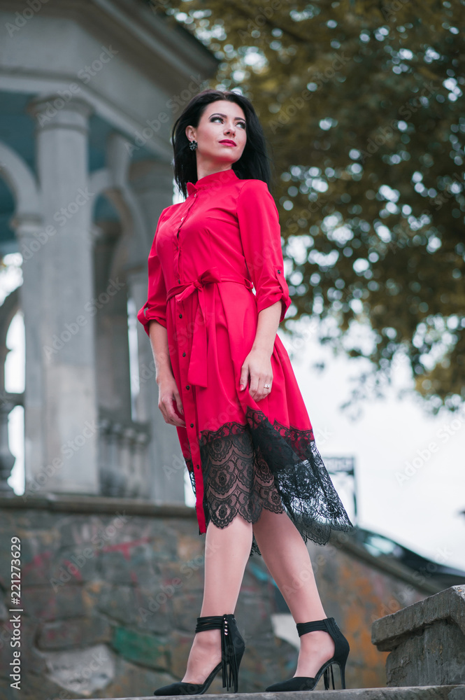 Vertical shot of attractive brunette woman in red dress walking in the city. Vertical shot of attractive brunette woman in red dress walking in the city.