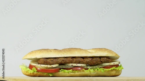 Turkish fast food Adana shish kebab in sandwich bread with vegetables. Rotating shot with copy space area for text.