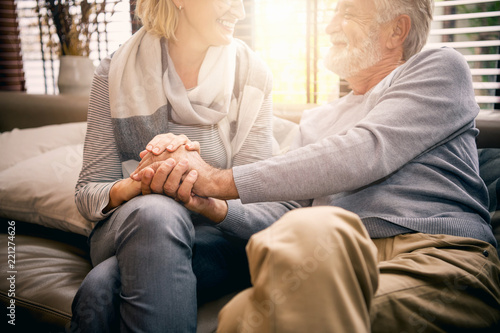 Romantic senior couple moment. The husband holds his wife's hand and talks about their love. Selective focus at her hand.