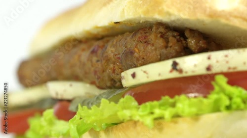 Turkish fast food Adana shish kebab in sandwich bread with vegetables. Rotating, slow motion, macro shot.