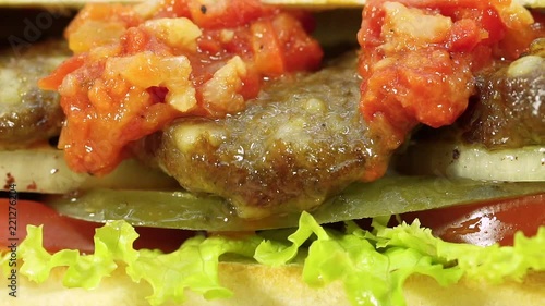 Turkish fast food meatball sandwich with cheese, red sauce with vegetables. Rotating shot.