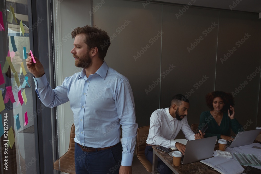 Architect checking sticky note while colleagues working in Architect checking sticky note while colleagues working in
