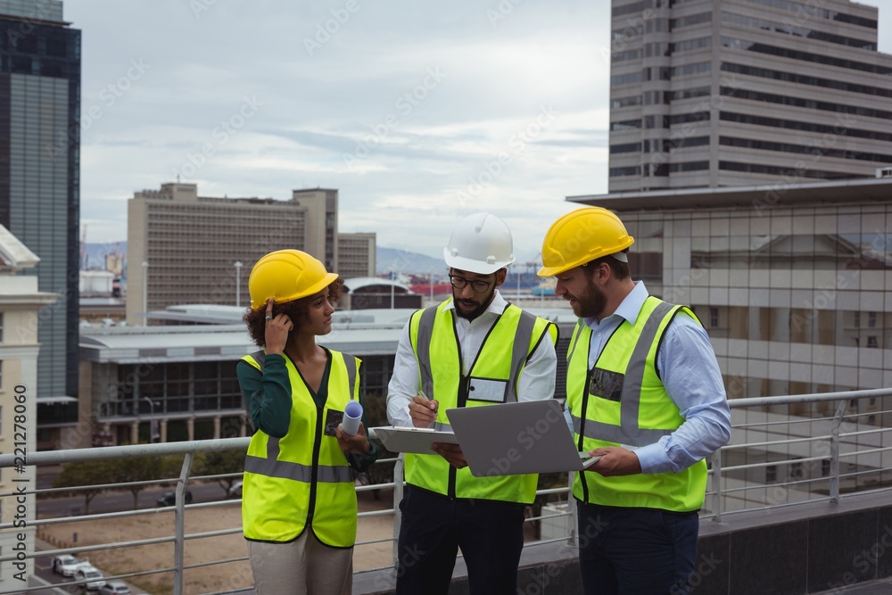 Architects with laptop discussing on clipboard Architects with laptop discussing on clipboard