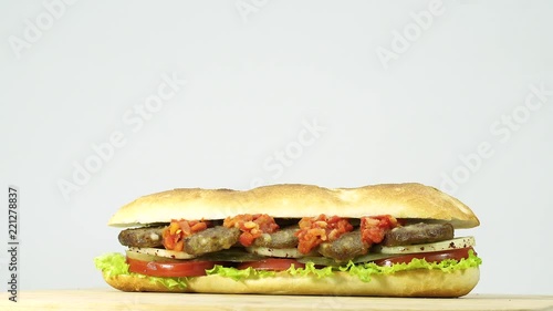 Turkish fast food meatball sandwich with cheese, red sauce with vegetables. Rotating shot.