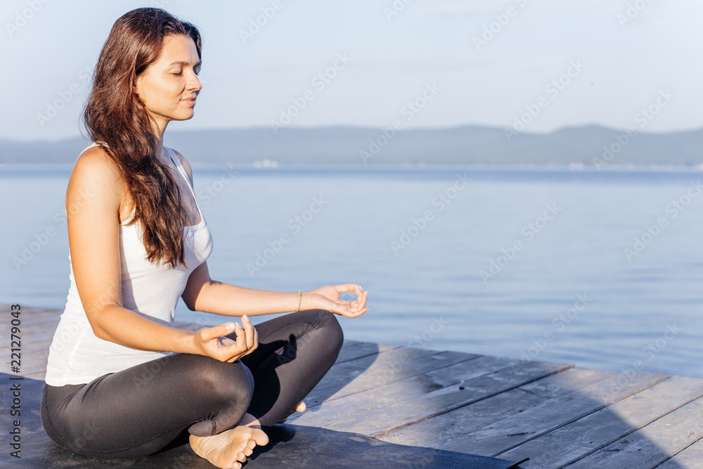 Young attractive smiling woman practicing yoga on a lake Young attractive smiling woman practicing yoga on a lake