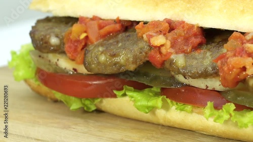 Turkish fast food meatball sandwich with cheese, red sauce with vegetables. Rotating shot.