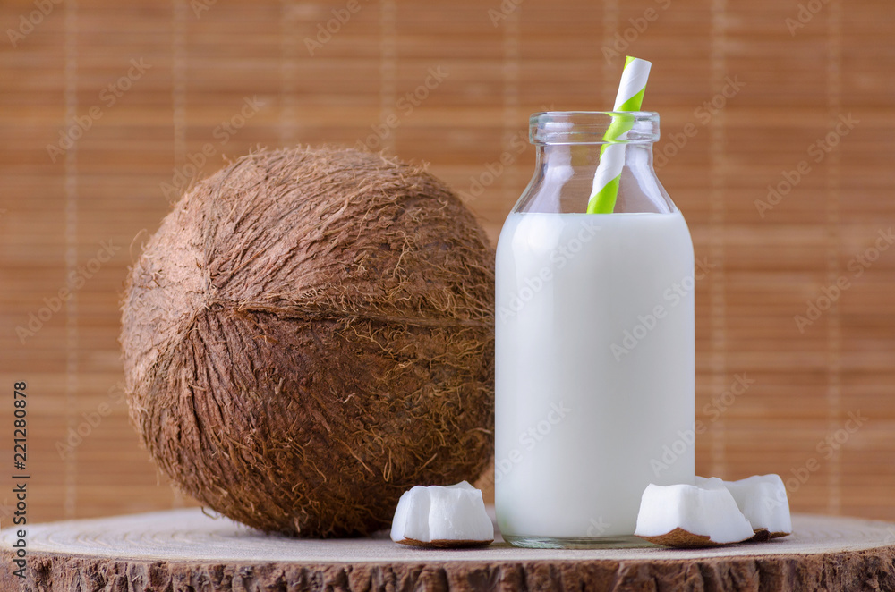 coconut milk in glass bottle with tubule on natural wooden brown background coconut milk in glass bottle with tubule on natural wooden brown background