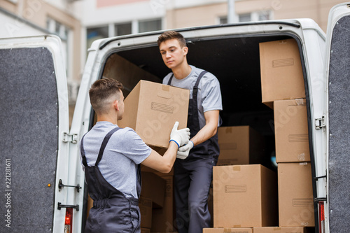 Two young handsome movers wearing uniforms are unloading the van photo