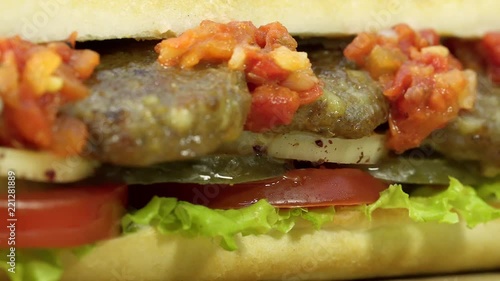 Turkish fast food meatball sandwich with cheese, red sauce with vegetables. Rotating shot.