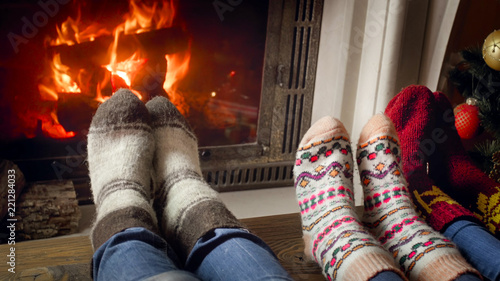 Closeup photo of three persons in woolen socks warming at the fireplace