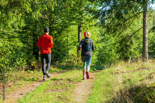 Kvinna och man joggar på en liten skogsväg