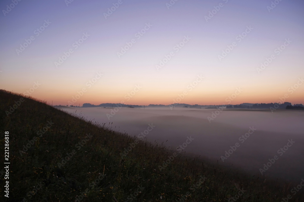 Colorful sunrise over rolling hills in the fog
