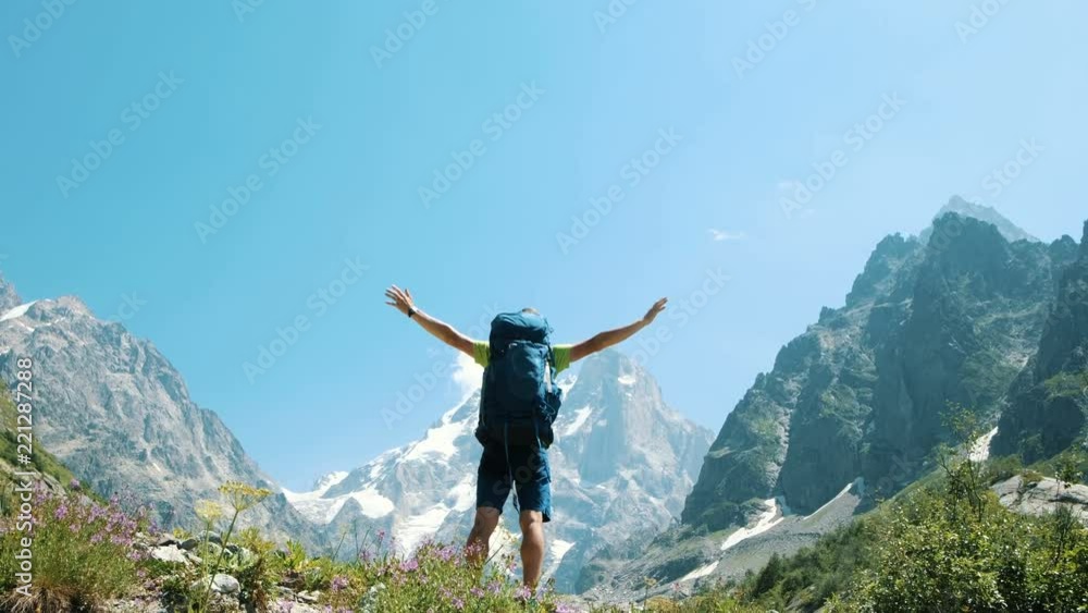 Man raises hands up in the mountains in a hike, a beautiful view opens up. Concept of victory and success, the achievement of the goal Man raises hands up in the mountains in a hike, a beautiful view opens up. Concept of victory and success, the achievement of the goal
