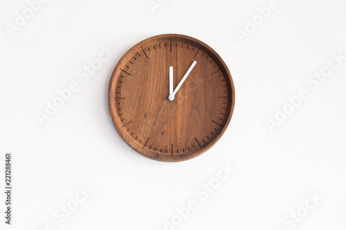round wooden clock on white concrete wall, show time on mid day for launch time.
