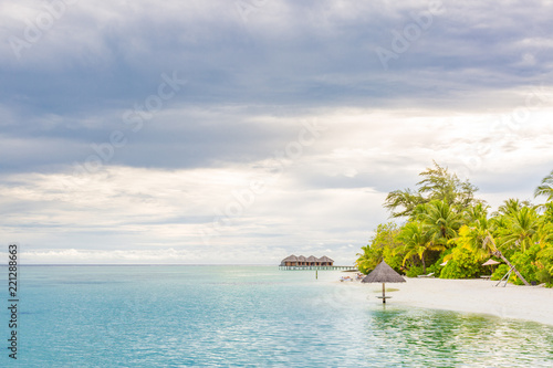 Beach umbrella on the beach atoll island Maldives. Calm tropical sunset